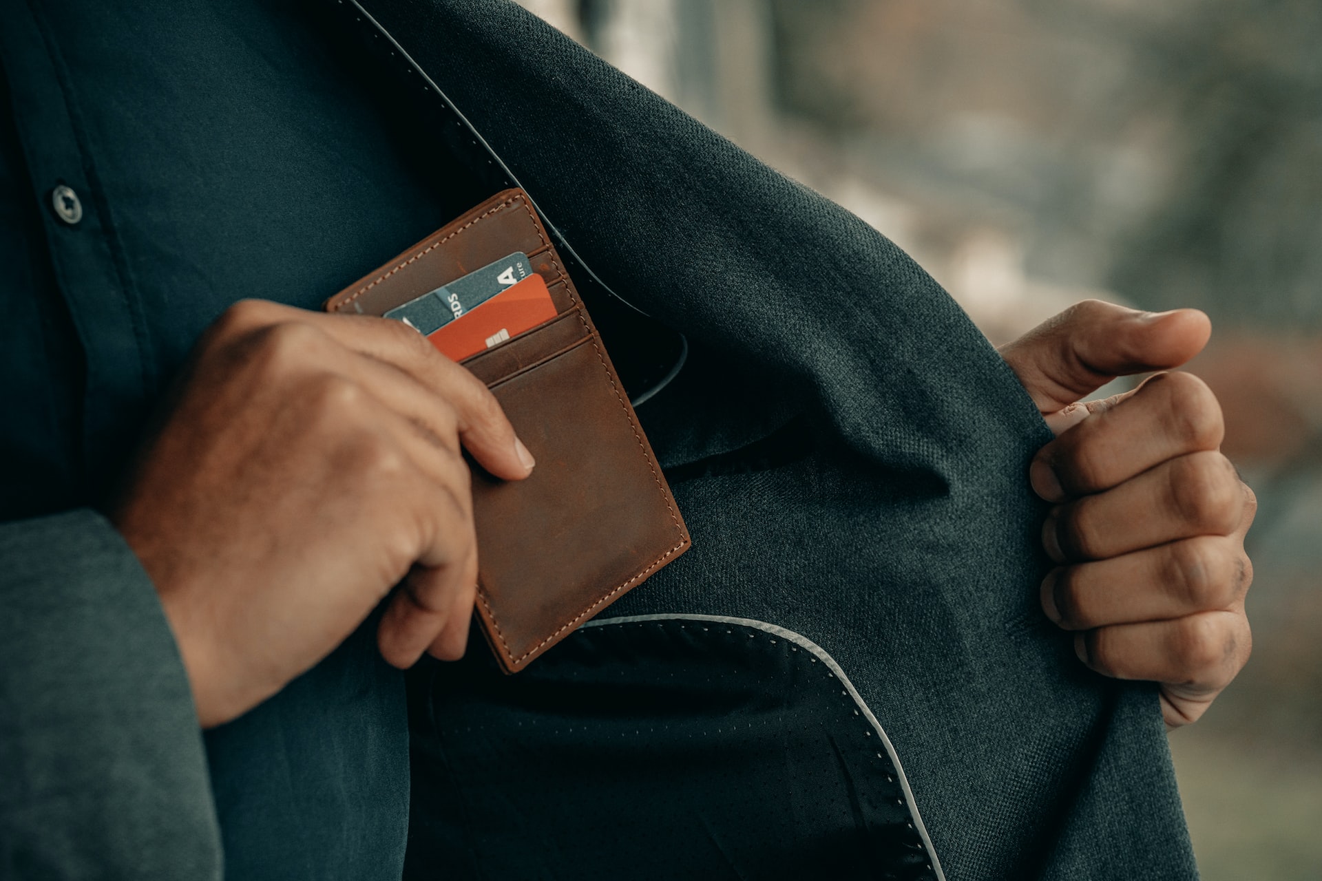 Man reaching into his jacket to remove a wallet with credit cards in it. Image is to illustrate the idea that no matter what, you will pay to publish your book.