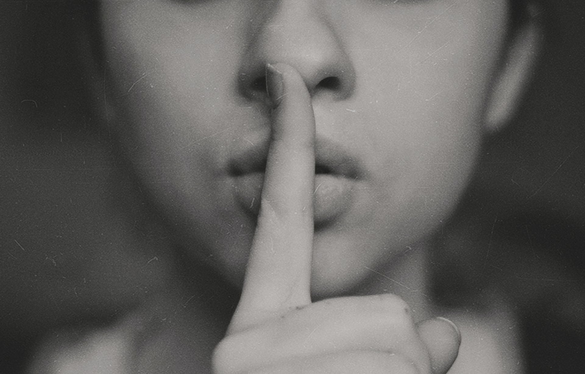 Picture of a woman with a finger over her mouth, showing that less dialogue can create a better book