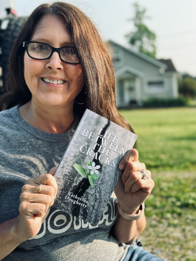 Katherine Daugherty holding her book Life Between the Cracks