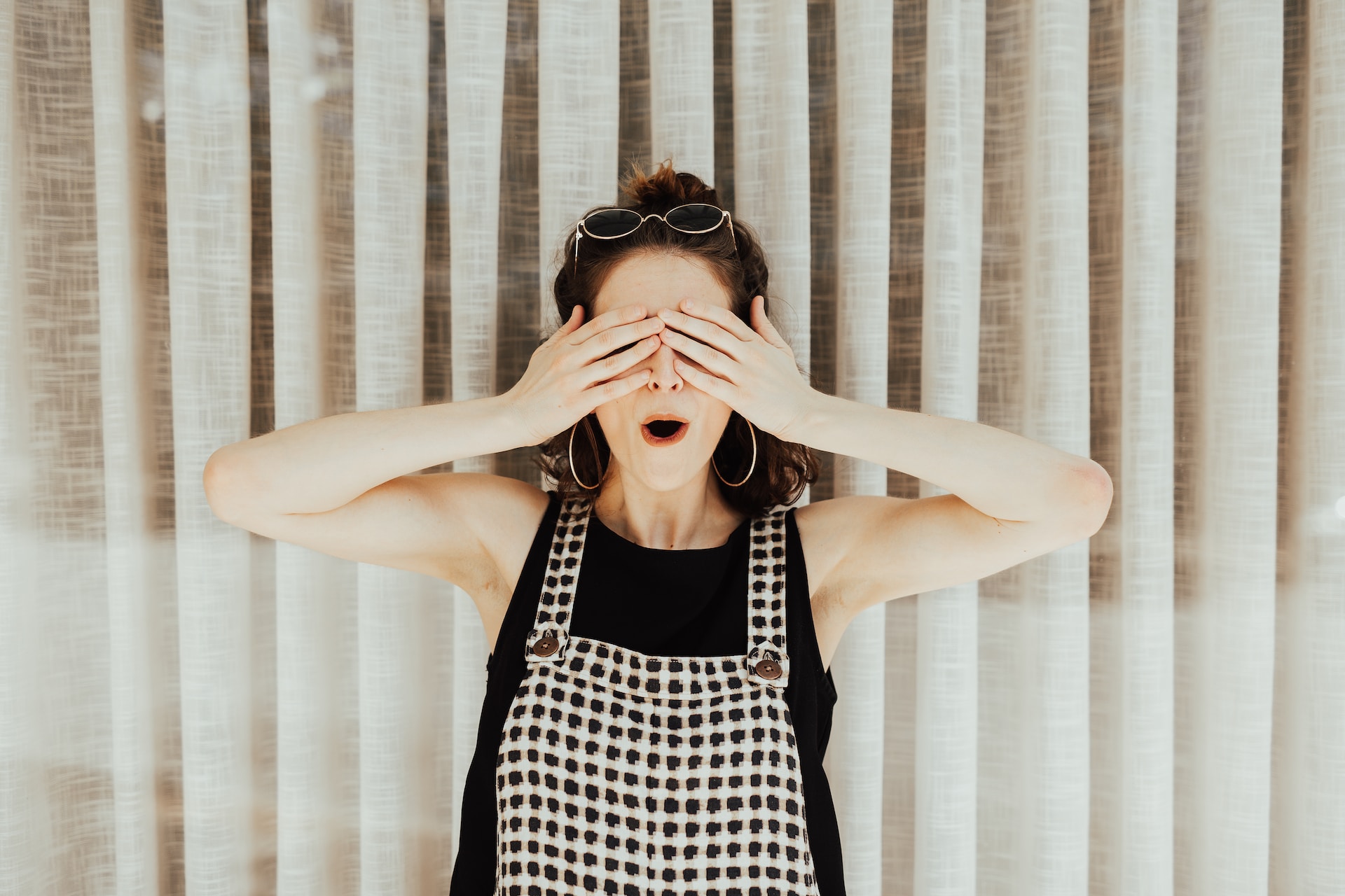 A young lady holds her hands over her eyes to show the idea of using a pen name (a made-up name authors use to disguise their identity).