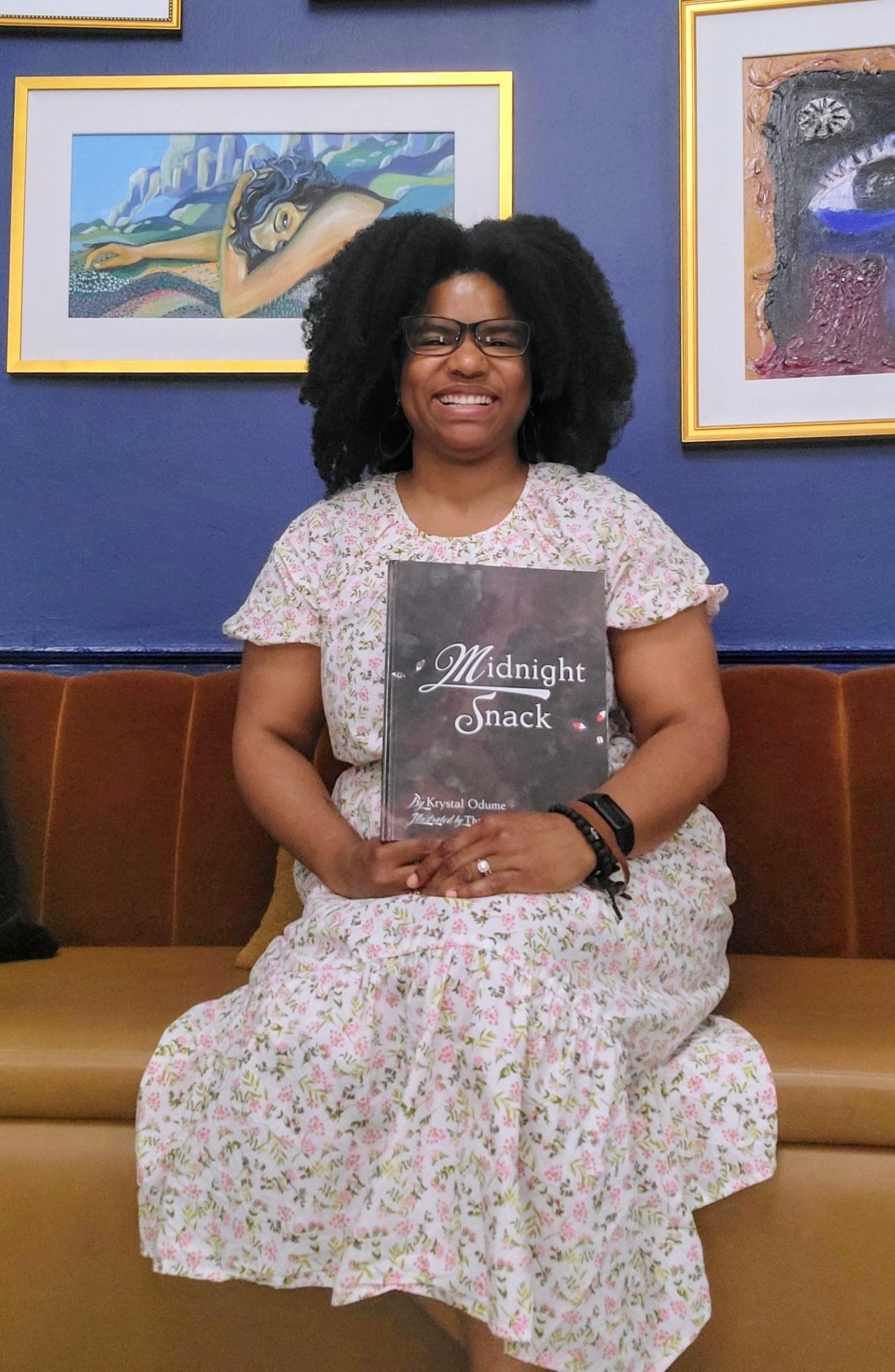 Picture book author Krystal Odume smiles and holds her children's book, Midnight Snack.