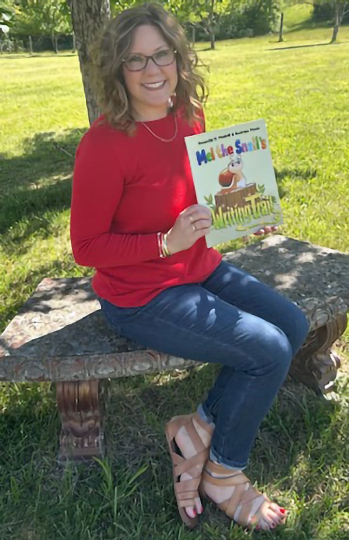 Middle grade fiction author Amanda H. Midkiff holds her first picture book, Mel the Snail's Writing Trail.