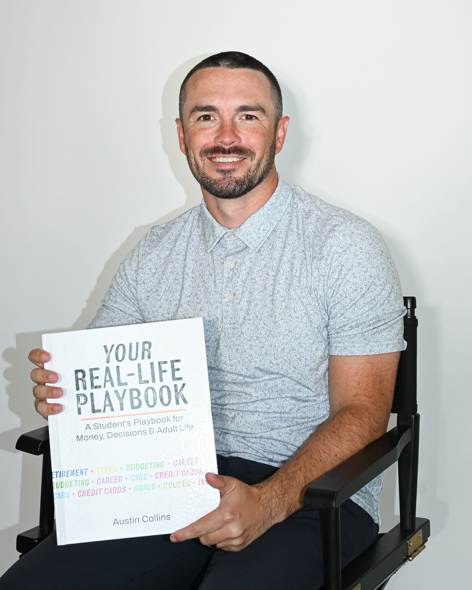 Financial education author Austin Collins holds his debut book, Your Real-Life Playbook: A Student's Playbook for Money, Decisions & Adult Life.